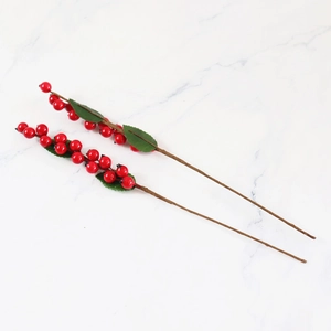 Artificial red Christmas berry branches with green leaves on marble background for home decor