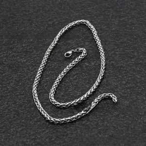Close-up of silver stainless steel wheat chain with lobster clasp on a stone background