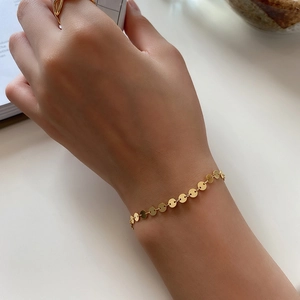 Close-up of minimalist 925 sterling silver gold disc bracelet worn on a female wrist