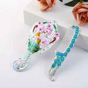 Detail of vintage silver hand mirror set with floral peacock enamel and matching comb