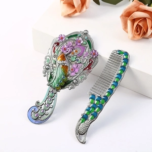 Detail of vintage peacock embossed metal hand mirror and comb set with enamel inlay