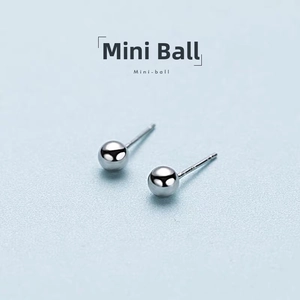 Macro shot of polished S925 sterling silver mini ball stud earrings on light blue background