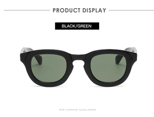 Detail of round black sunglasses with dark green lenses and stylish metal accents