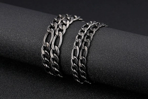 Macro view of vintage silver Figaro link chains on a black cylindrical display stand
