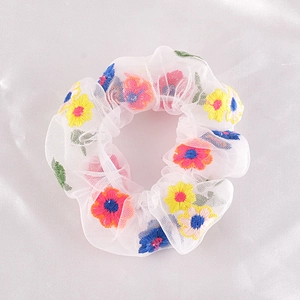 Close-up of white mesh hair scrunchie with colorful embroidered daisy flower patterns