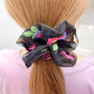 Daisy embroidered black mesh scrunchie hair tie shown on a model ponytail
