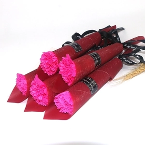 Detailed view of five pink carnation soap bouquets wrapped in sparkly red paper with ribbons