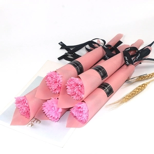 Detail of pink artificial soap carnations with decorative black ribbons on white desk