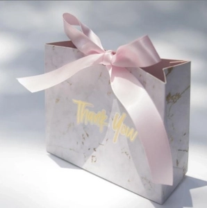 Detail of marble pattern wedding candy box featuring elegant pink ribbon and gold Thank You text