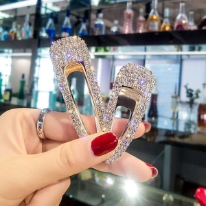 Close-up of sparkling rhinestone hair clips in hand showing premium metal base