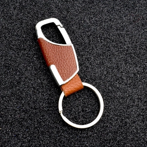 Detail of brown leather car keychain with polished silver metal spring buckle on black background
