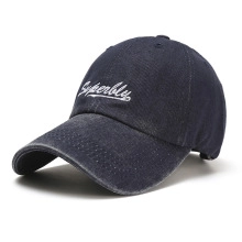 Detail of white Superbly embroidery on vintage washed denim baseball cap with curved brim