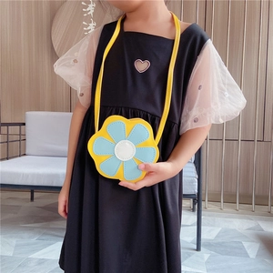 Détail du sac bandoulière en forme de fleur avec lanière jaune sur un mannequin enfant