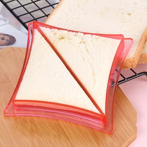 Detail of red plastic sandwich cutter shaping triangular white bread on wooden board