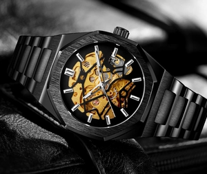 Close-up of men's hollow skeleton watch showing golden mechanical movement and black metal case