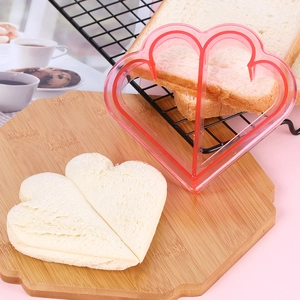 Pink heart-shaped plastic sandwich cutter shown with a freshly pressed toast slice