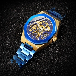 Macro shot of mechanical skeleton watch with blue bezel and gold gear movement mechanism