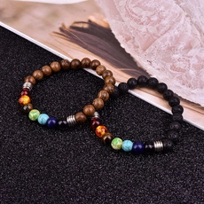 Detalle de pulseras de madera marrón y piedra de lava negra con cuentas de chakra