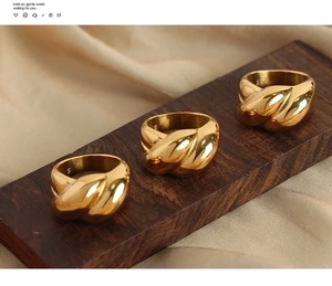 Macro detail of high-polish gold plated twisted rope rings on a wooden display stand