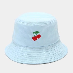 Détail de la broderie cerise sur un chapeau bob en toile de coton bleu clair