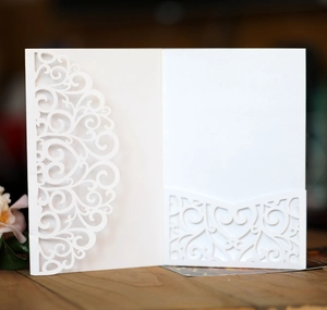 Detail of white laser-cut wedding invitation card with intricate hollow heart patterns