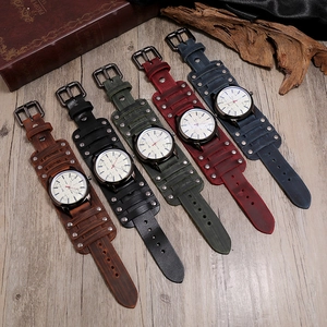 Five punk style leather watches with metal studs displayed on a rustic wood background