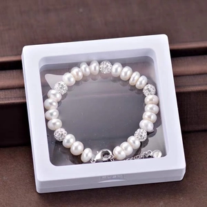 Macro detail of a pearl bracelet displayed in a transparent PE film floating storage box