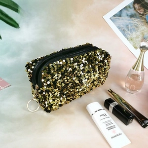 Detail of shimmering gold sequin makeup bag featuring a metallic ring zipper puller