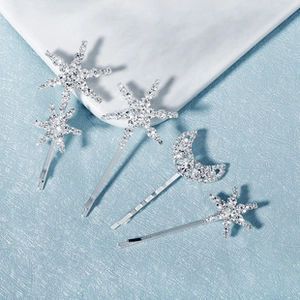 Detailed view of silver rhinestone star and moon hair clips set on a ceramic base