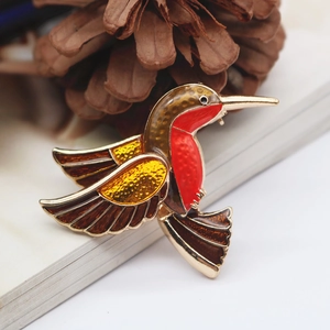 Vibrant enamel hummingbird brooch with red and yellow wings on a golden alloy base
