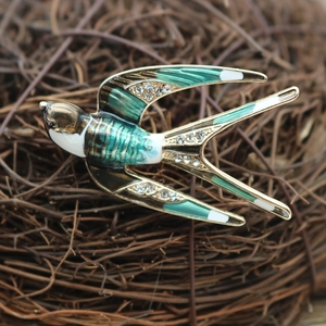 Macro detail of enamel swallow bird brooch with white rhinestones on a rustic bird nest