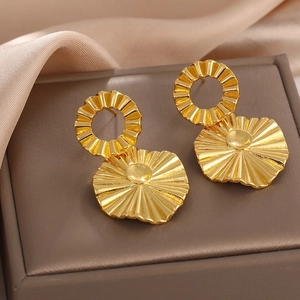 Detailed view of textured golden wave earrings with a radiating pattern in a jewelry box