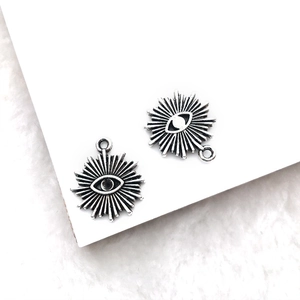 Close-up of silver-tone Eye of Horus charms with sunburst design for DIY jewelry