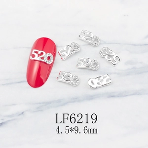 Detailed view of silver 520 nail charm with rhinestones on red nail and marble background
