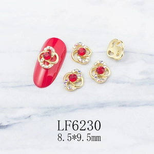Detailed view of hollow flower nail charms with red rhinestones and gold base accents