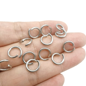 Multiple silver stainless steel open jump rings held by hand for jewelry DIY size reference
