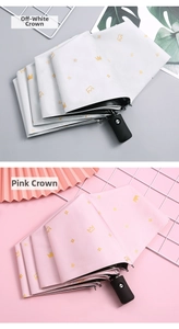 Close-up of cream and pink automatic folding umbrellas with golden crown patterns