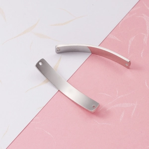Close-up of two curved rectangular stainless steel connectors with holes for DIY jewelry