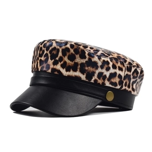 Detail of leopard print military cap with black leather brim and gold side buttons