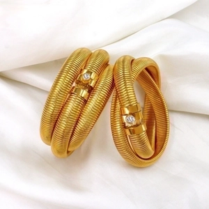 Macro detail of golden Tubogas spiral bracelet featuring a clear zircon inlay connector