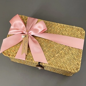 Detailed texture of rectangular woven seagrass gift box with pink bow and tag