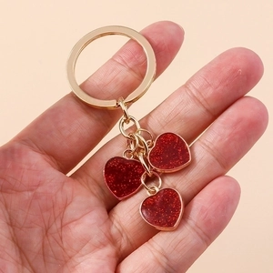Golden heart keychain featuring three red sparkling glitter pendants for handbags