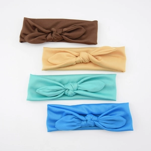 Flat lay of four elastic knotted baby headbands in brown, beige, turquoise, and blue colors