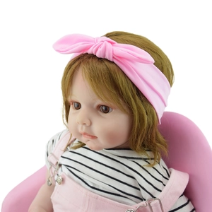 Detailed view of a soft pink knotted bunny ear headband for babies on a doll model