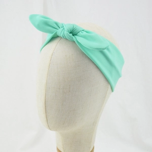 Detail view of a mint green knotted bunny ear headband for babies on a model head