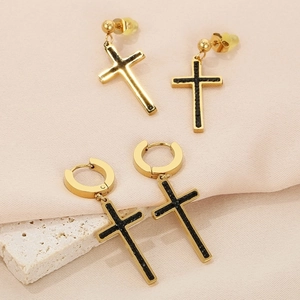 Detailed view of gold cross earrings with black inlay on silk and stone background