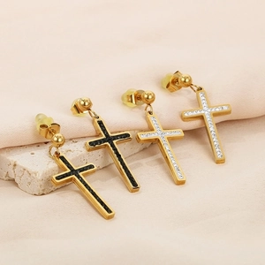 Macro shot of gold cross earrings with inlaid black and white cubic zirconia stones
