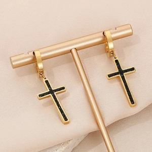 Close-up of gold cross earrings with black rhinestones on a metal jewelry stand