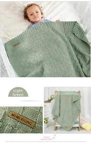 Detail of light green knitted baby blanket with checkerboard texture and leather tag