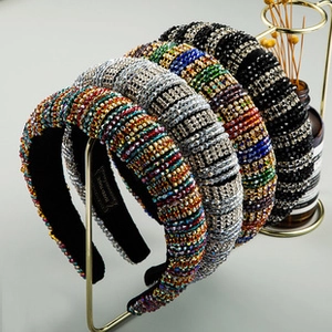 Detail of five padded headbands with colorful rhinestones on a gold metal stand